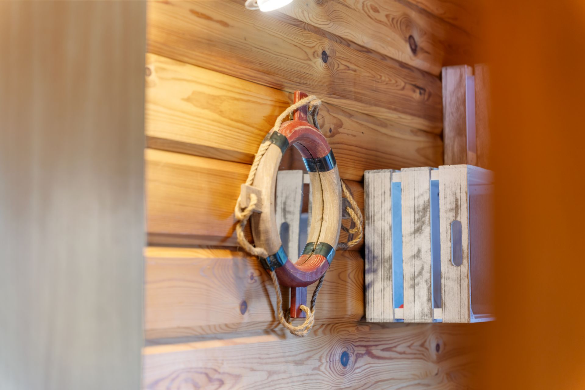 Rettungsring und Holzkisten an einer Wand aus Holzbohlen.