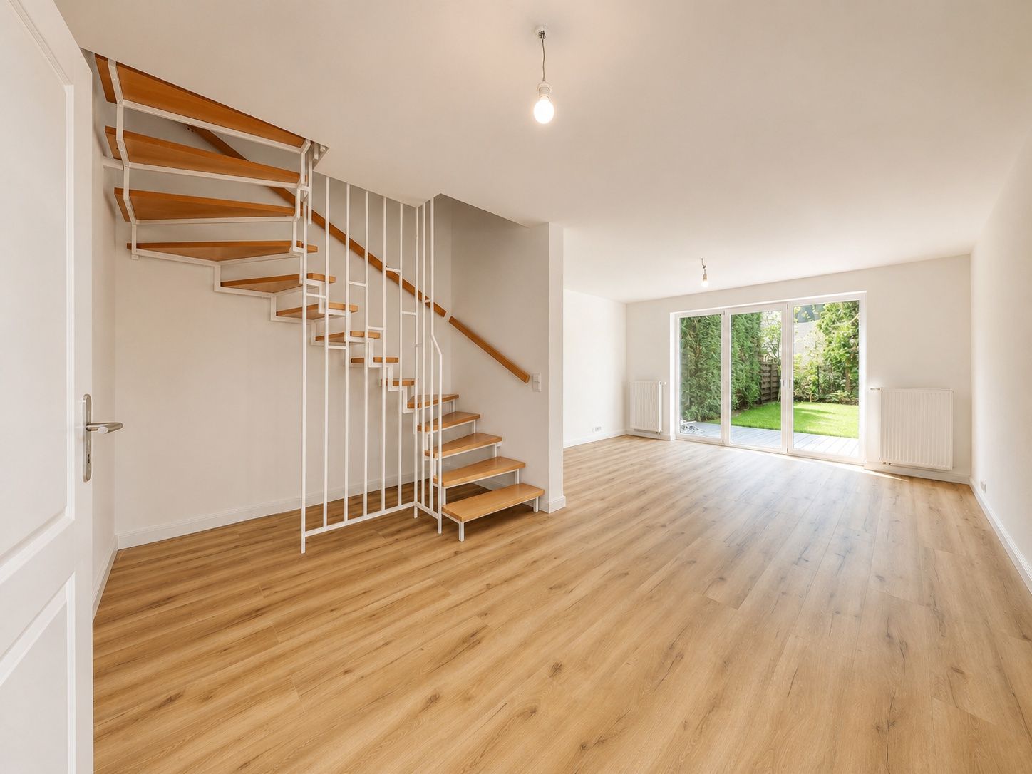 Helles Wohnzimmer mit Holztreppe, großem Fenster und Blick auf den Garten.