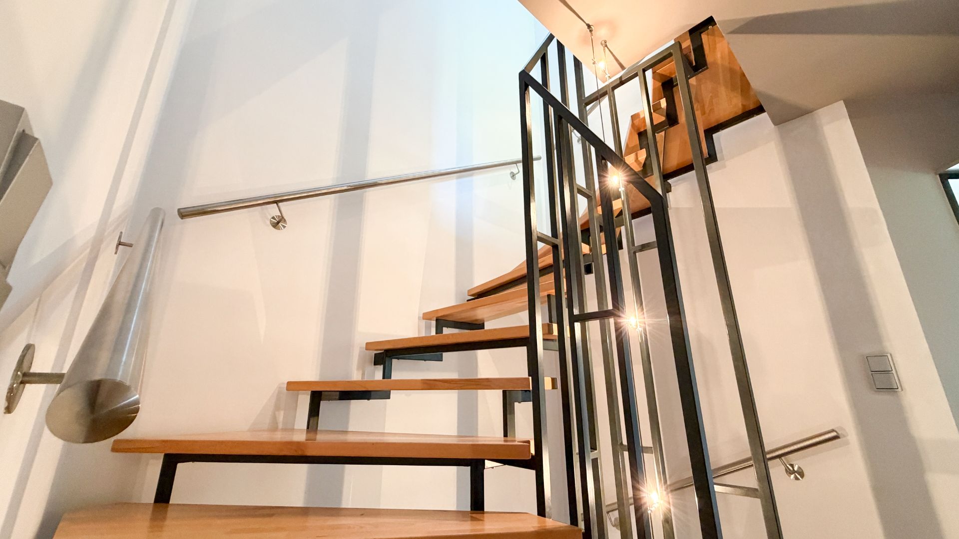Moderne Holztreppe mit Metallgeländer in einem hellen Innenraum.