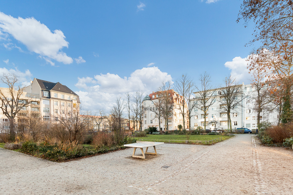 Wohngebäude mit Gartenbereich, einem Tischtennistisch und kahlen Bäumen bei Tageslicht.