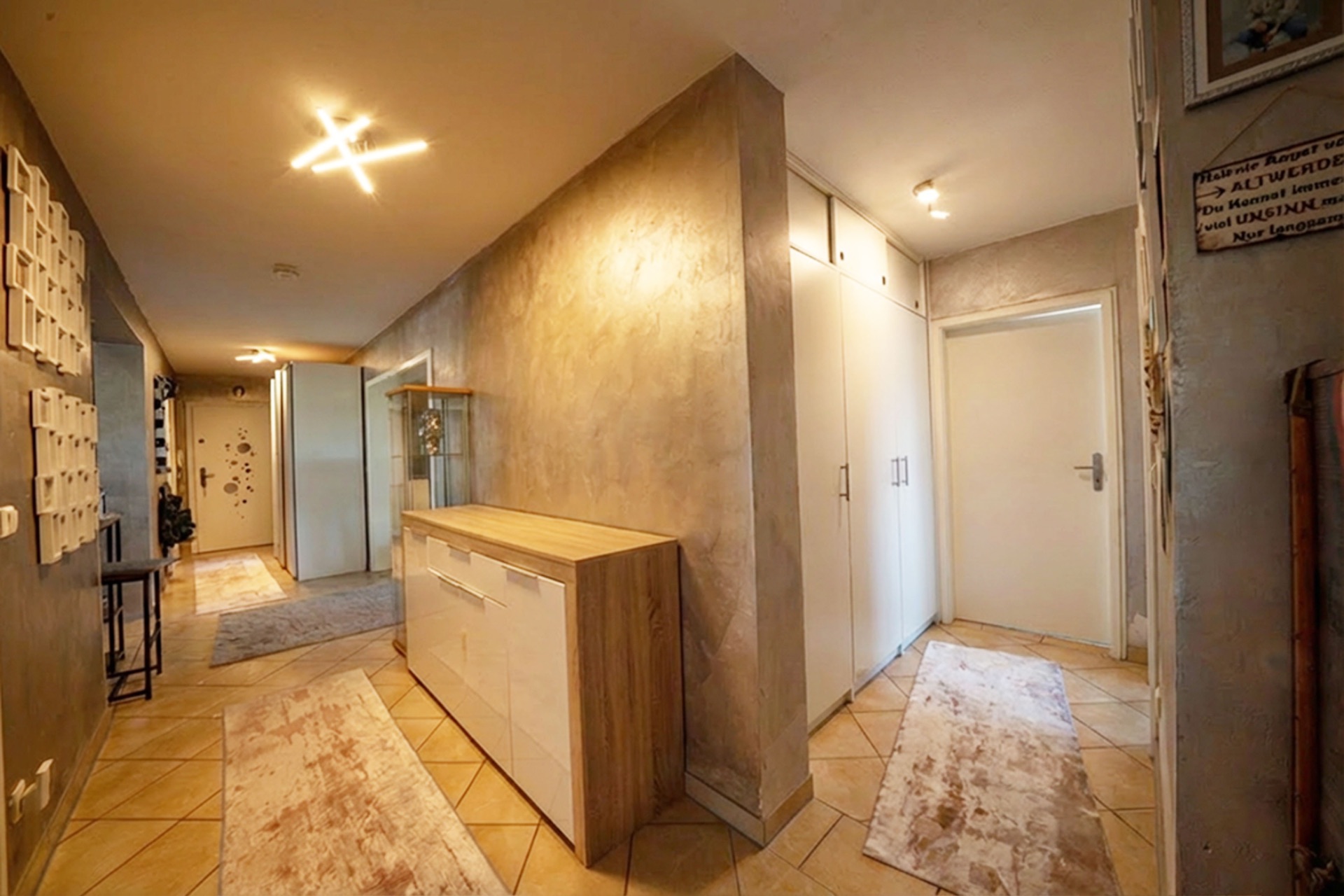 Heller Flur mit Kommode, Teppichen und Einbauschränken in einer Wohnung.