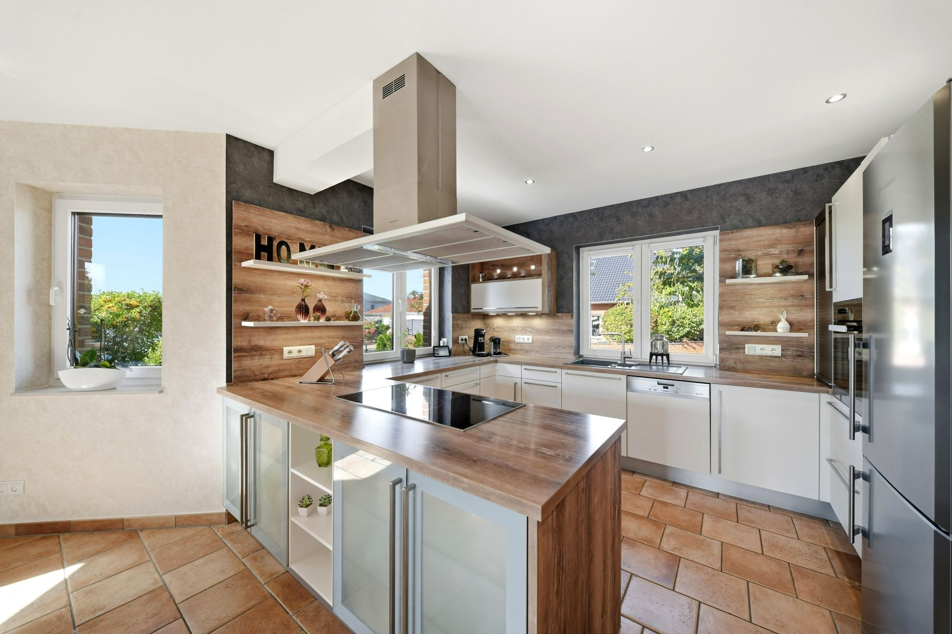 Moderne Wohnküche mit Kochinsel, großen Fenstern und Holzdetails.