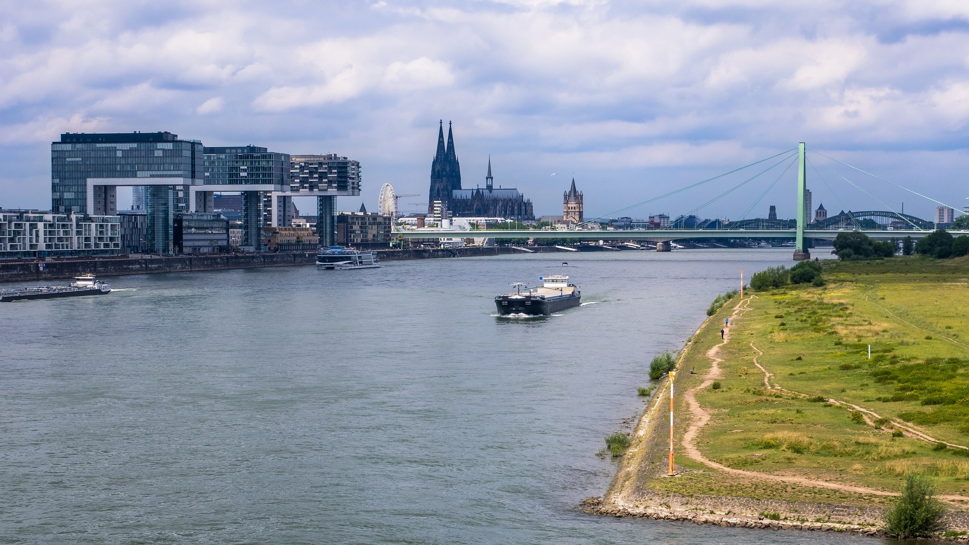 Großer Fluss mit Schiffen, moderner Architektur und einer Brücke im Hintergrund.