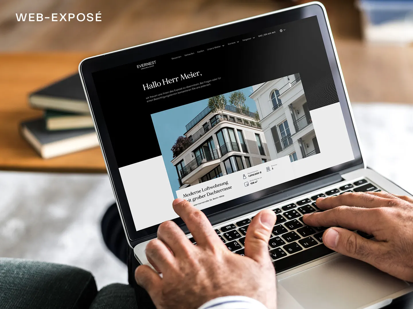Person nutzt Laptop, auf dem Immobilienanzeige mit modernem Wohngebäude angezeigt wird.