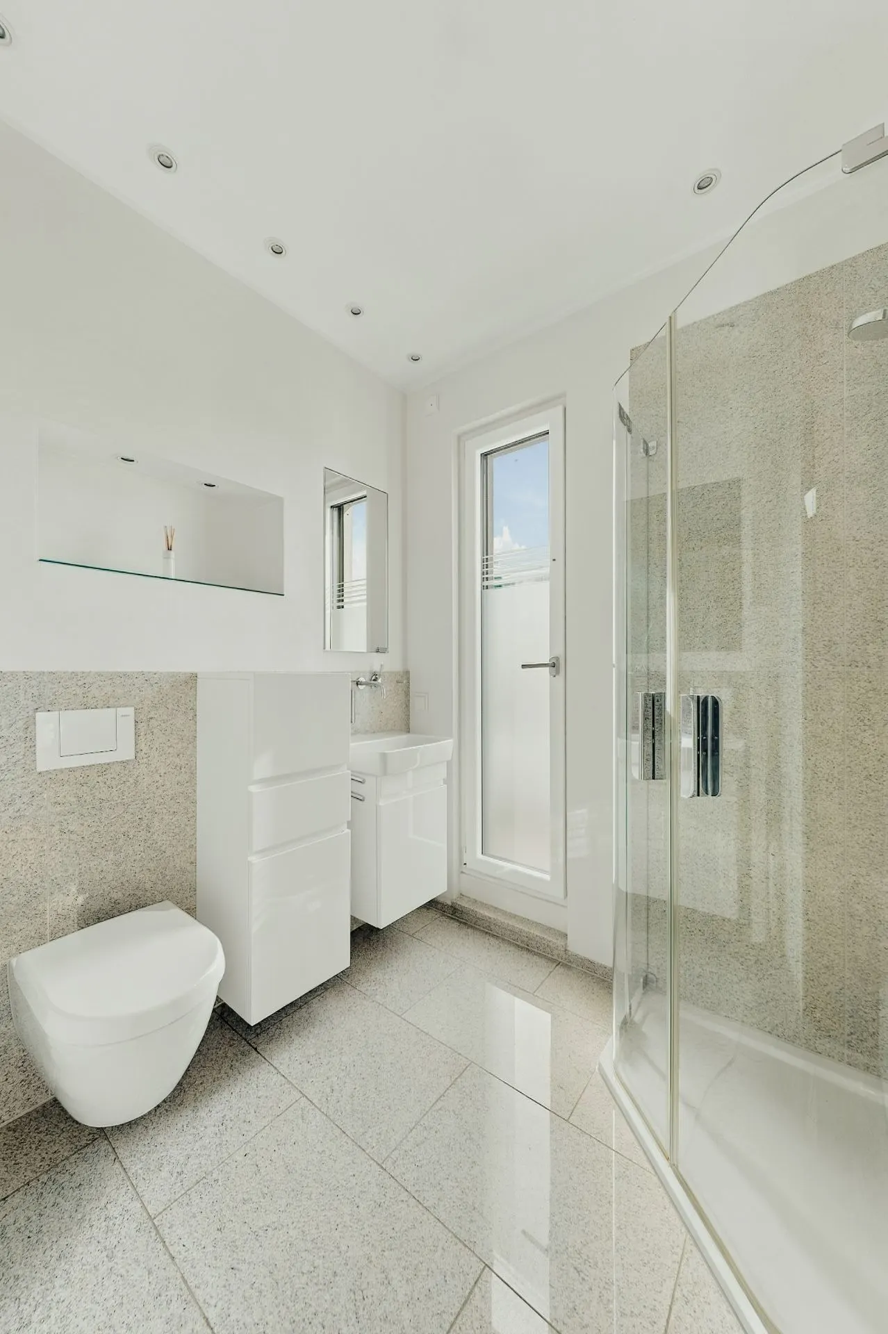 Modernes Badezimmer mit Dusche, WC, Waschbecken und großem Fenster.
