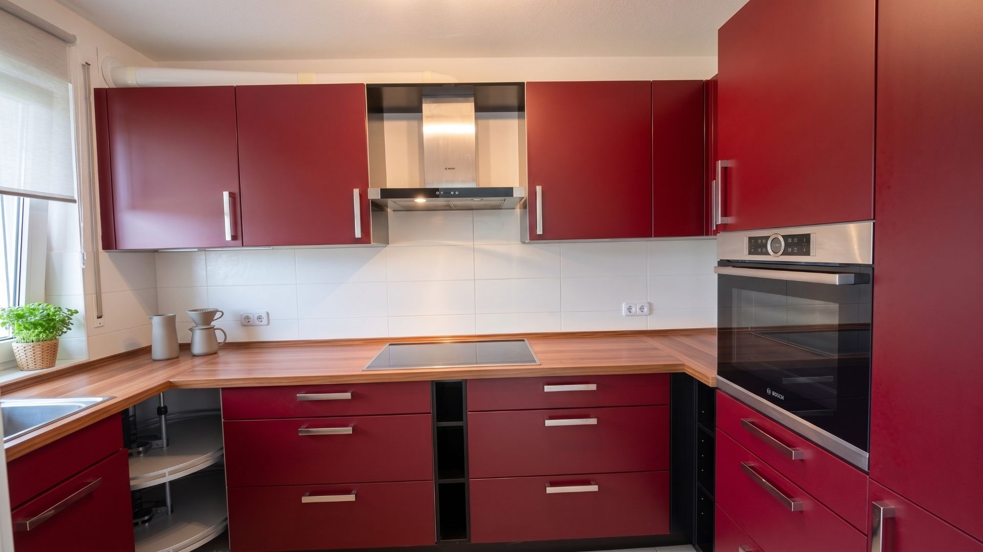 Moderne Küche mit roten Schränken, Holzarbeitsplatte, Herd und Backofen.