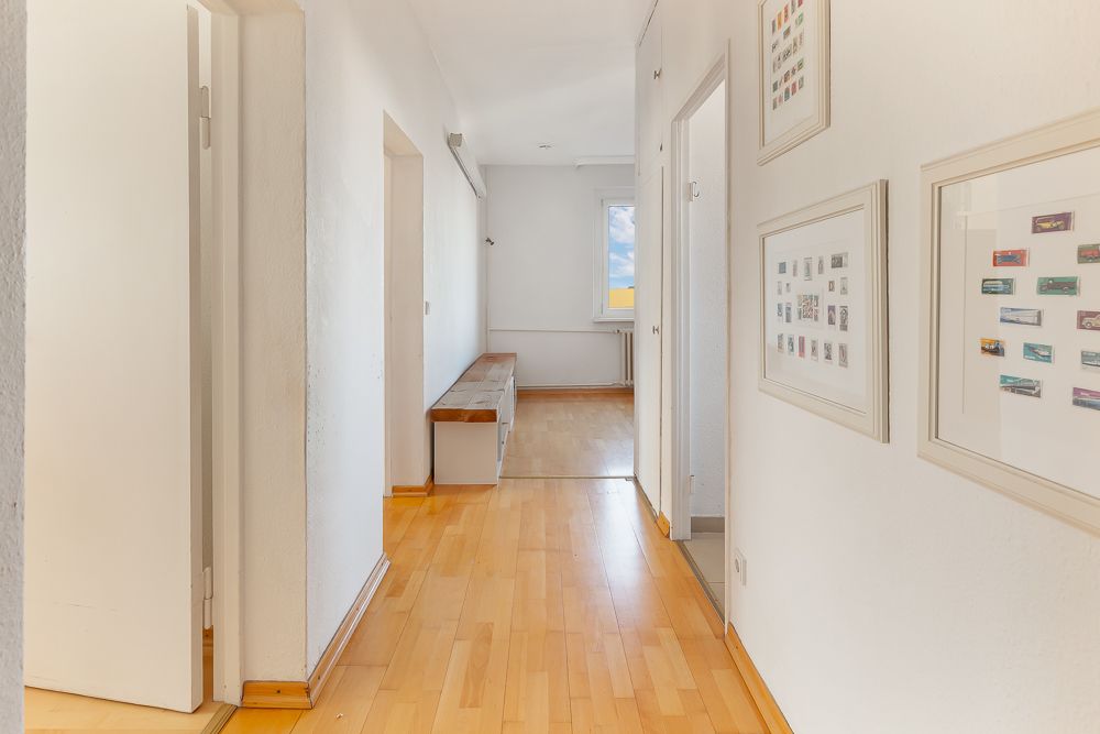 Heller Flur mit Holzfußboden, Türen zu mehreren Zimmern und Bildern an der Wand.