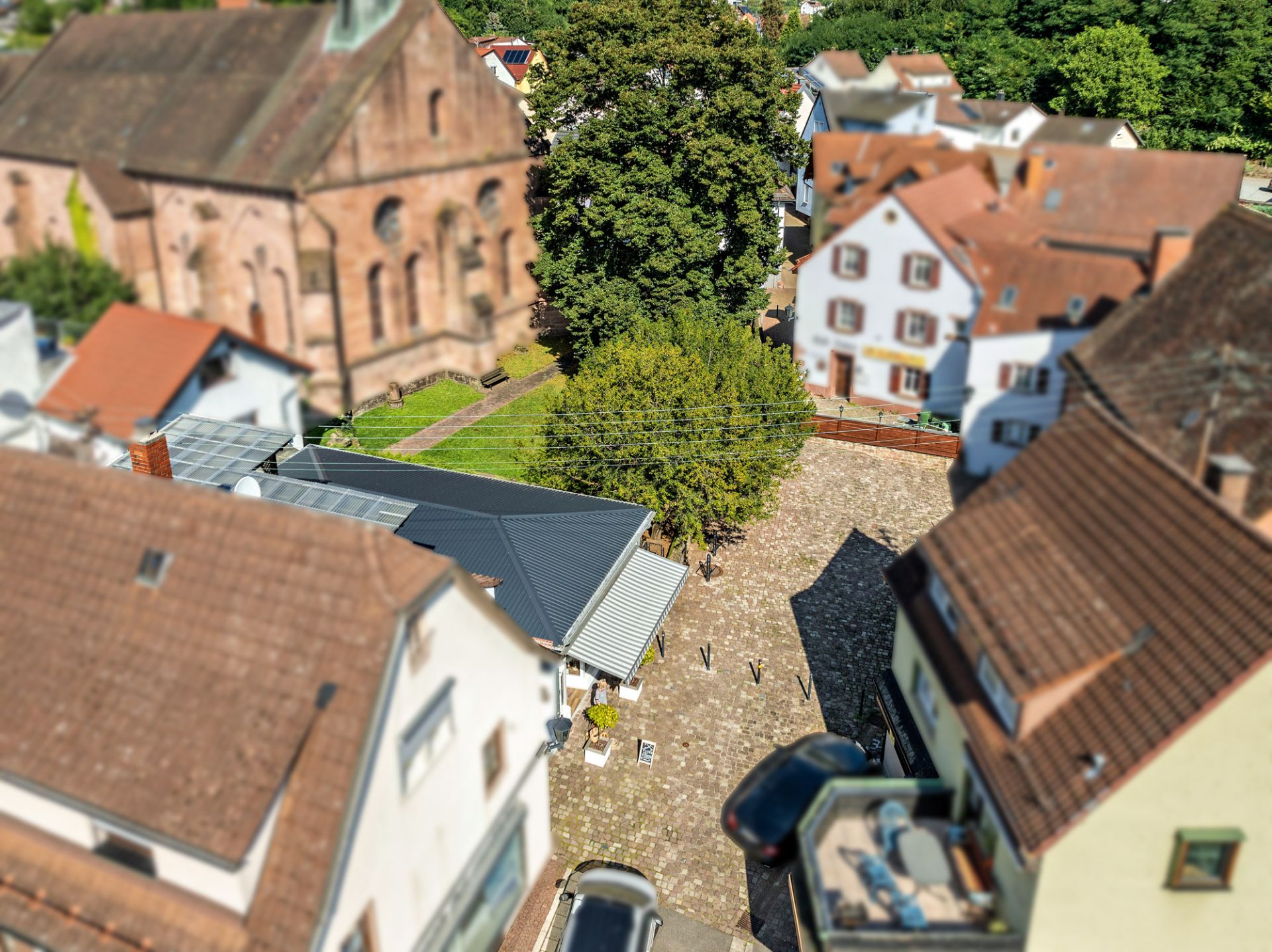 Blick von oben auf einen gepflasterten Innenhof mit Bäumen und umgebenden Wohnhäusern.