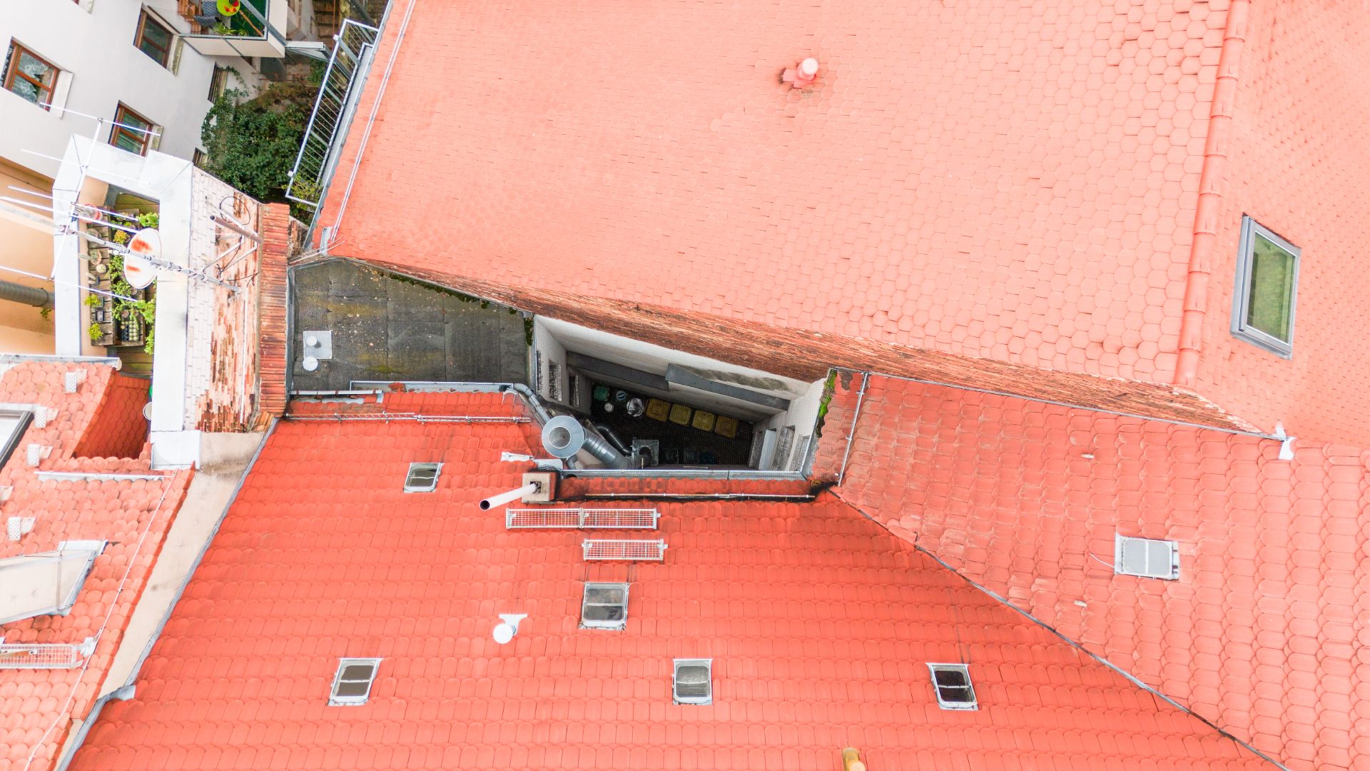 Blick von oben auf ein Gebäude mit roten Dachziegeln und kleinem Innenhof.