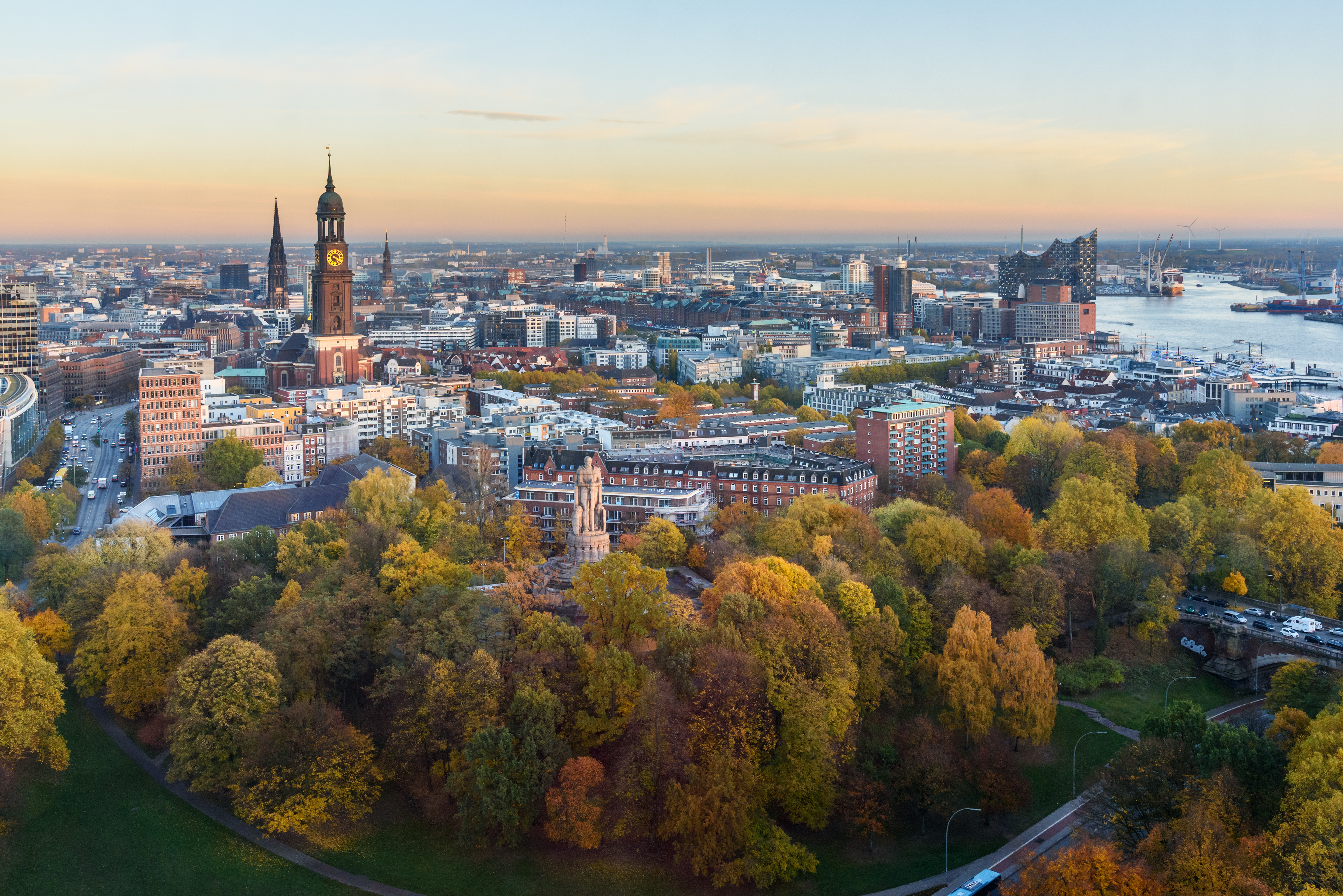 Blick über eine Stadt mit vielen Bäumen und einem Fluss im Hintergrund.