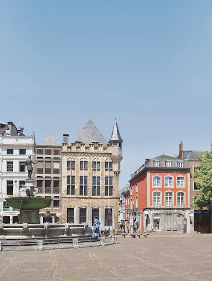 Historischer Platz mit Brunnen und mehrstöckigen Wohngebäuden bei sonnigem Wetter.