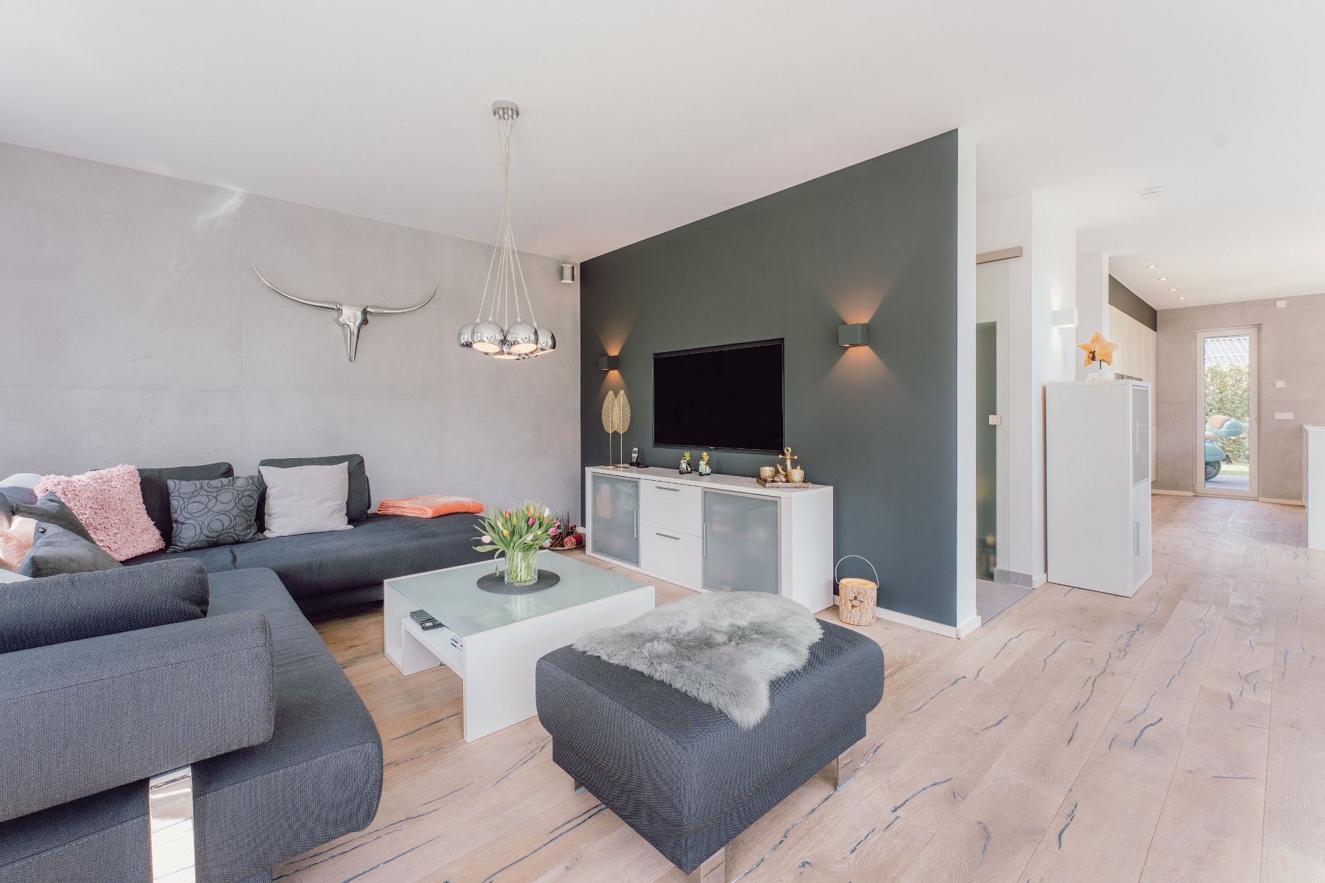 Modernes Wohnzimmer mit Ecksofa, Couchtisch, Fernseher und dekorativer Wand.