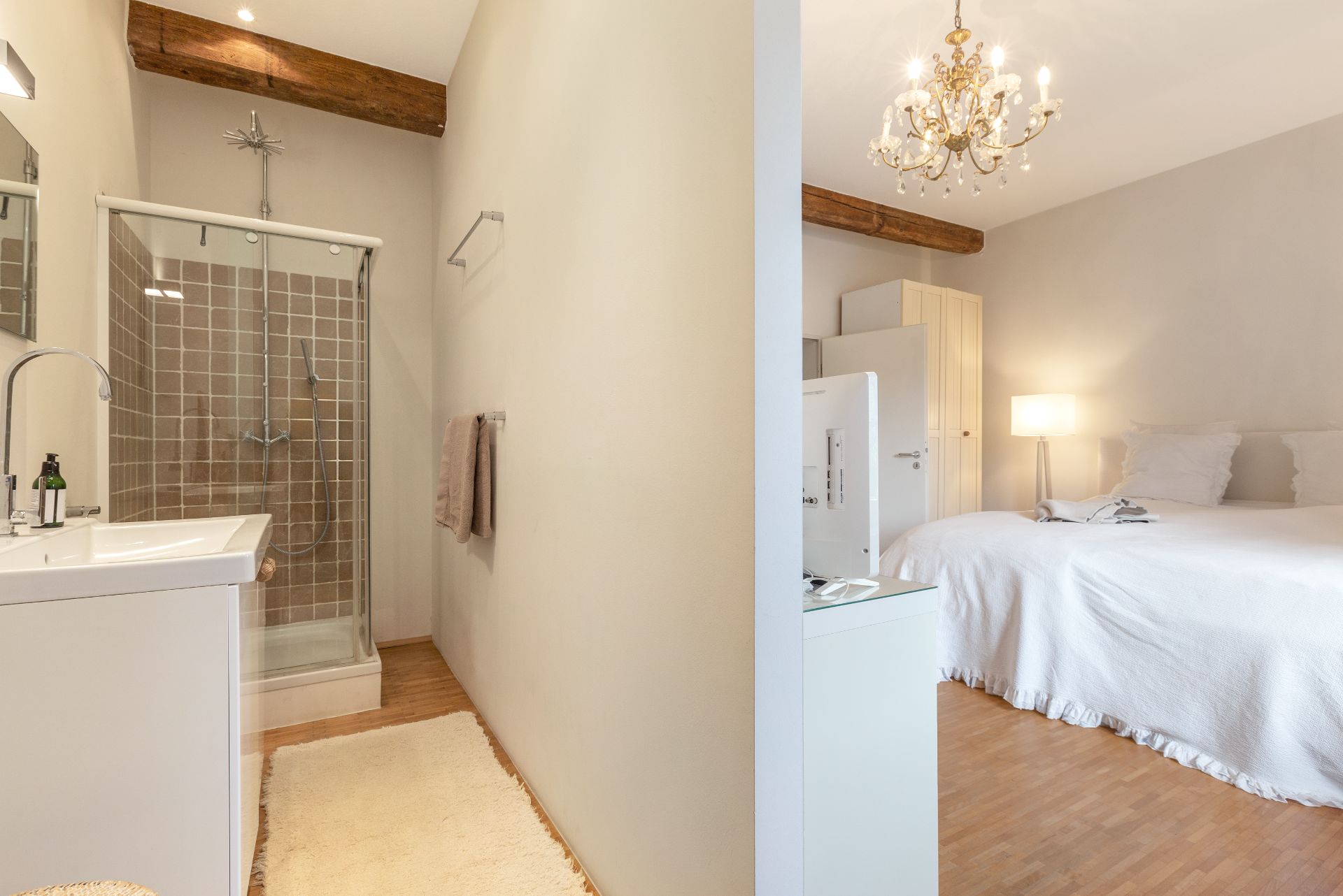 Schlafzimmer mit Doppelbett und angrenzendem Badezimmer mit Dusche und Waschbecken.