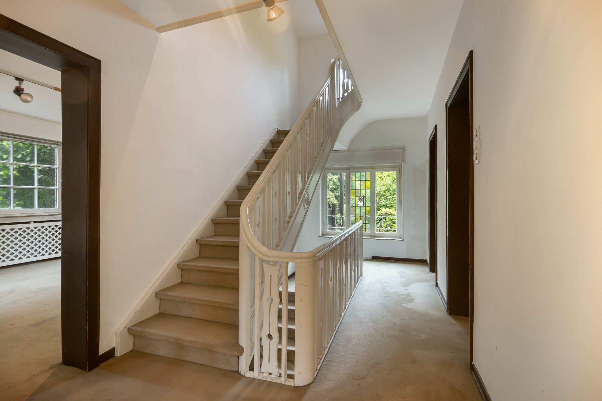 Heller Flur mit Treppe, großem Fenster und Türen zu angrenzenden Zimmern.