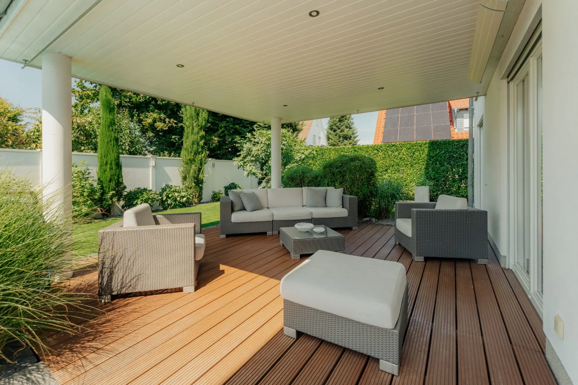 Überdachte Terrasse mit Gartenmöbeln und Blick auf einen gepflegten Garten.