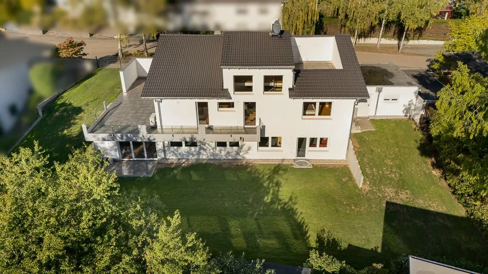 Modernes zweistöckiges Wohnhaus mit Terrasse und großem Garten, aus der Vogelperspektive fotografiert.