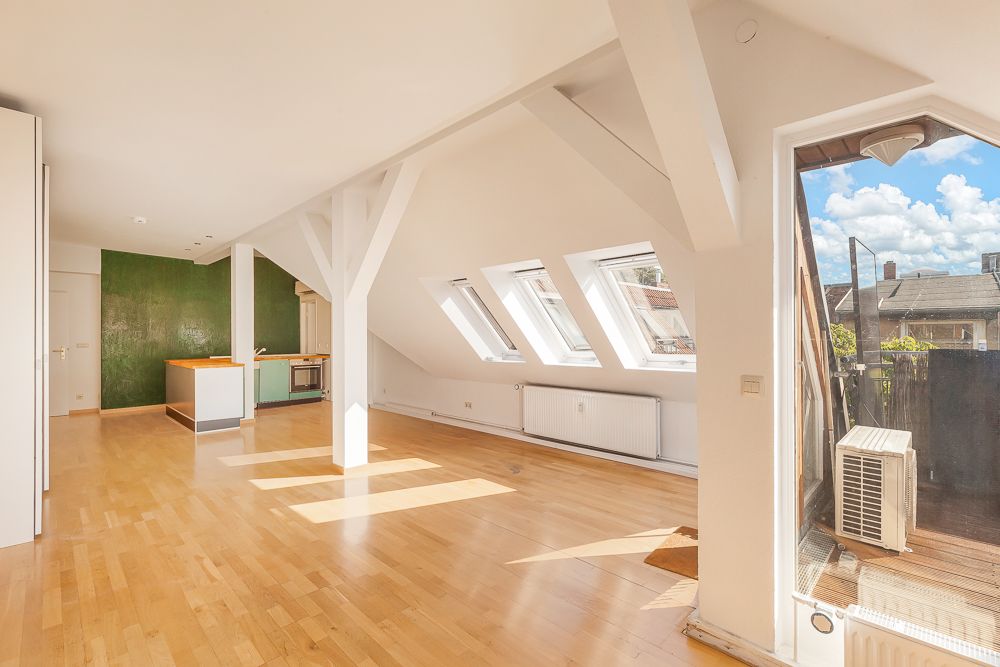 Helles Wohnzimmer mit Holzfußboden, Dachfenstern und Zugang zu einem Balkon.