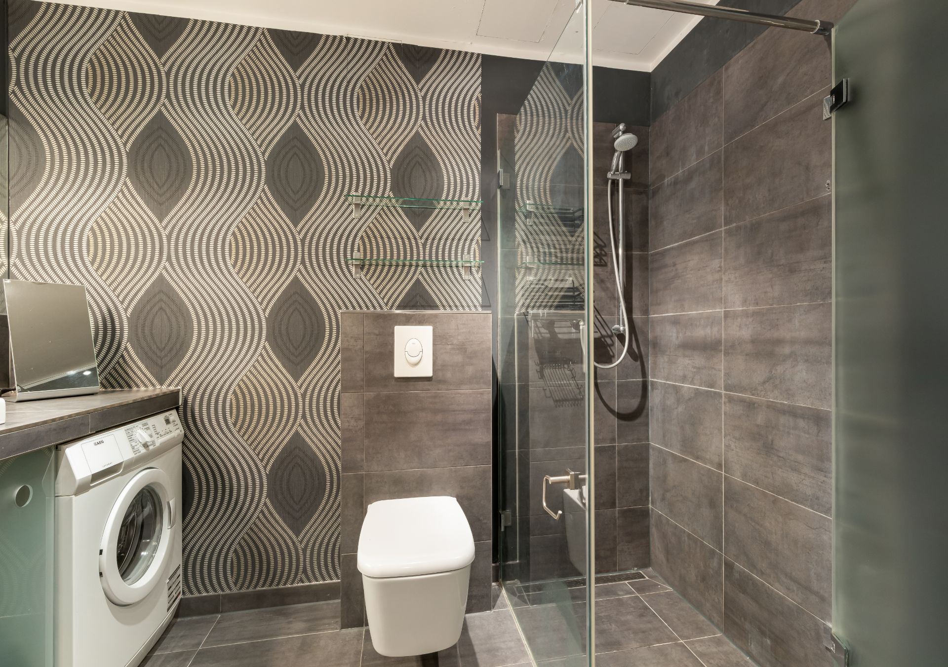 Modernes Badezimmer mit Dusche, Toilette, Waschmaschine und gemusterter Tapete.