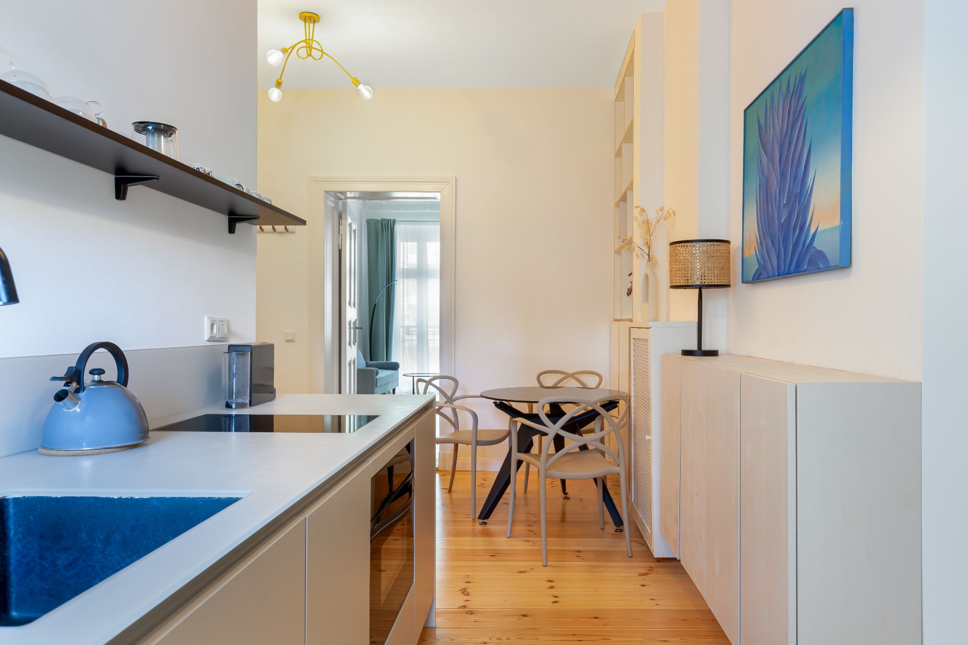 Moderne Küche mit Esstisch und vier Stühlen, heller Holzboden, Gemälde an der Wand.