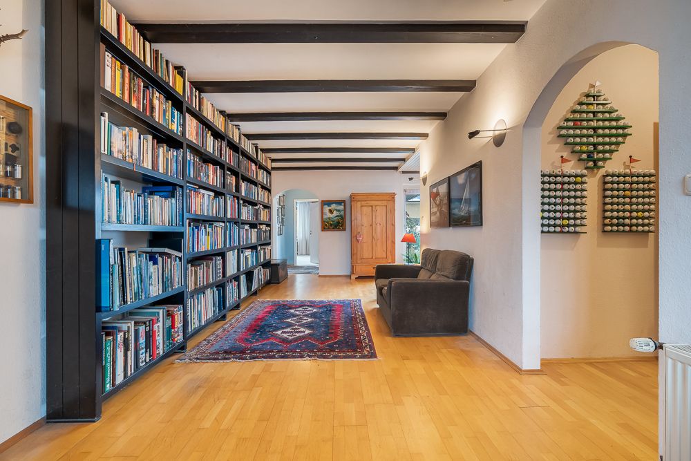 Flur mit Bücherregal, Sofa, Teppich und Holzboden, Wanddekorationen an den Wänden.