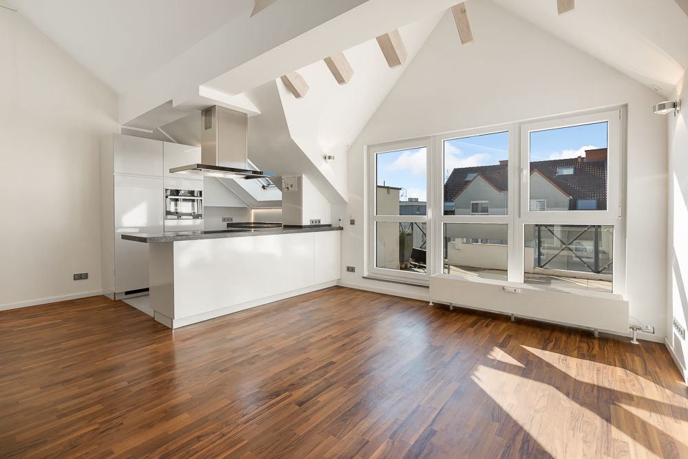 Helles Wohnzimmer mit offener moderner Küche, Holzfußboden und großen Fenstern.