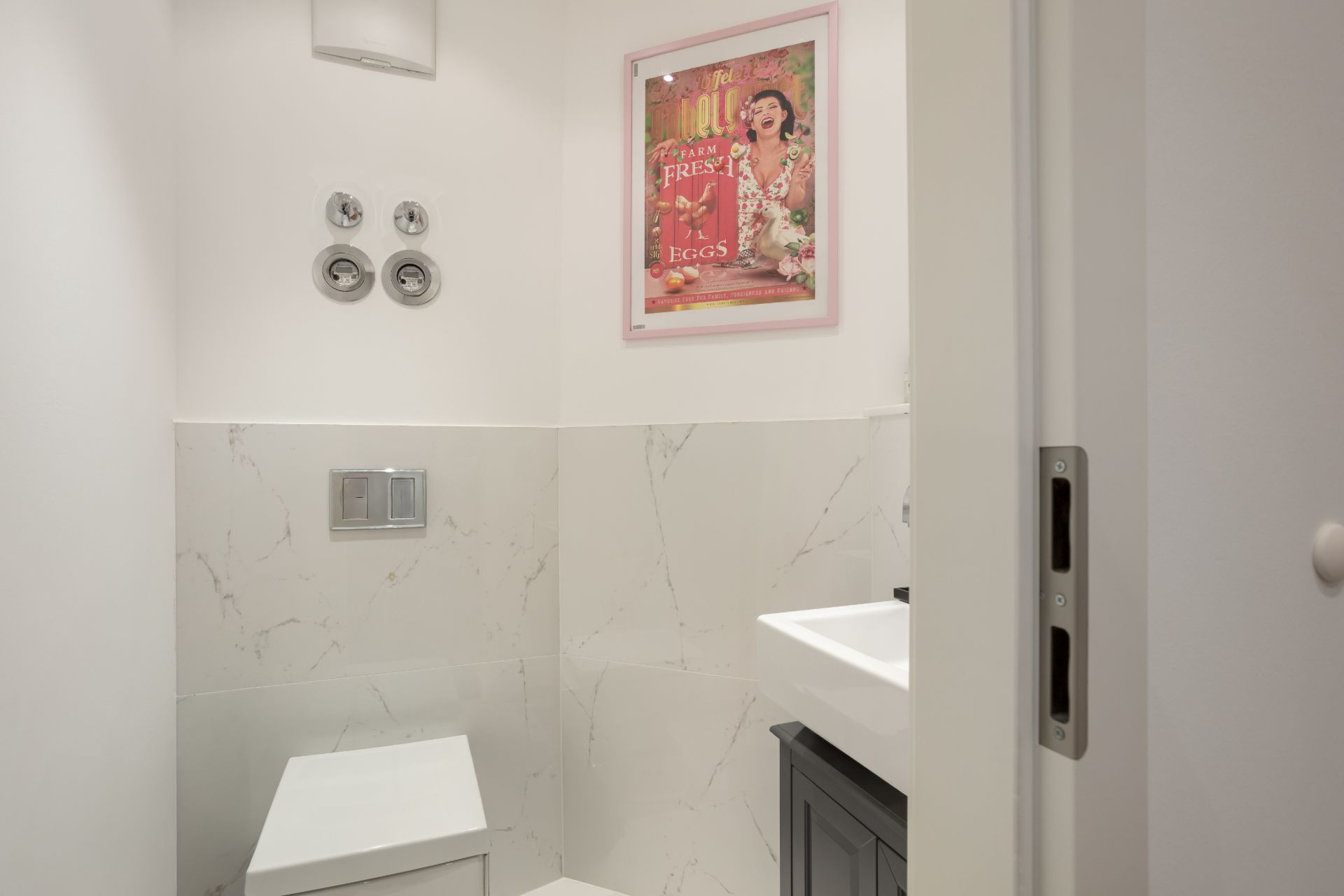 Kleines Badezimmer mit Toilette, Waschbecken und Bild an der Wand.
