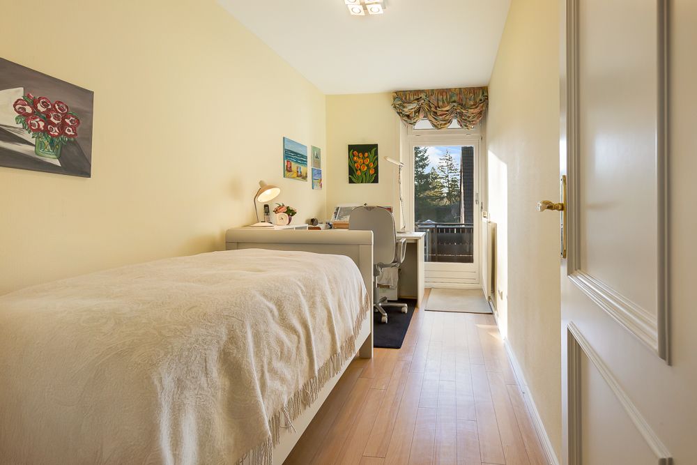Helles, schmales Schlafzimmer mit Einzelbett, Schreibtisch und Tür zum Balkon.