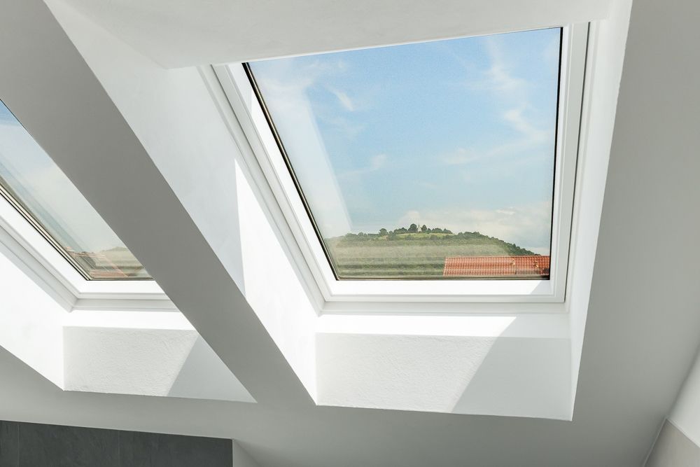 Zwei große Dachfenster lassen viel Licht in einen weißen Raum.