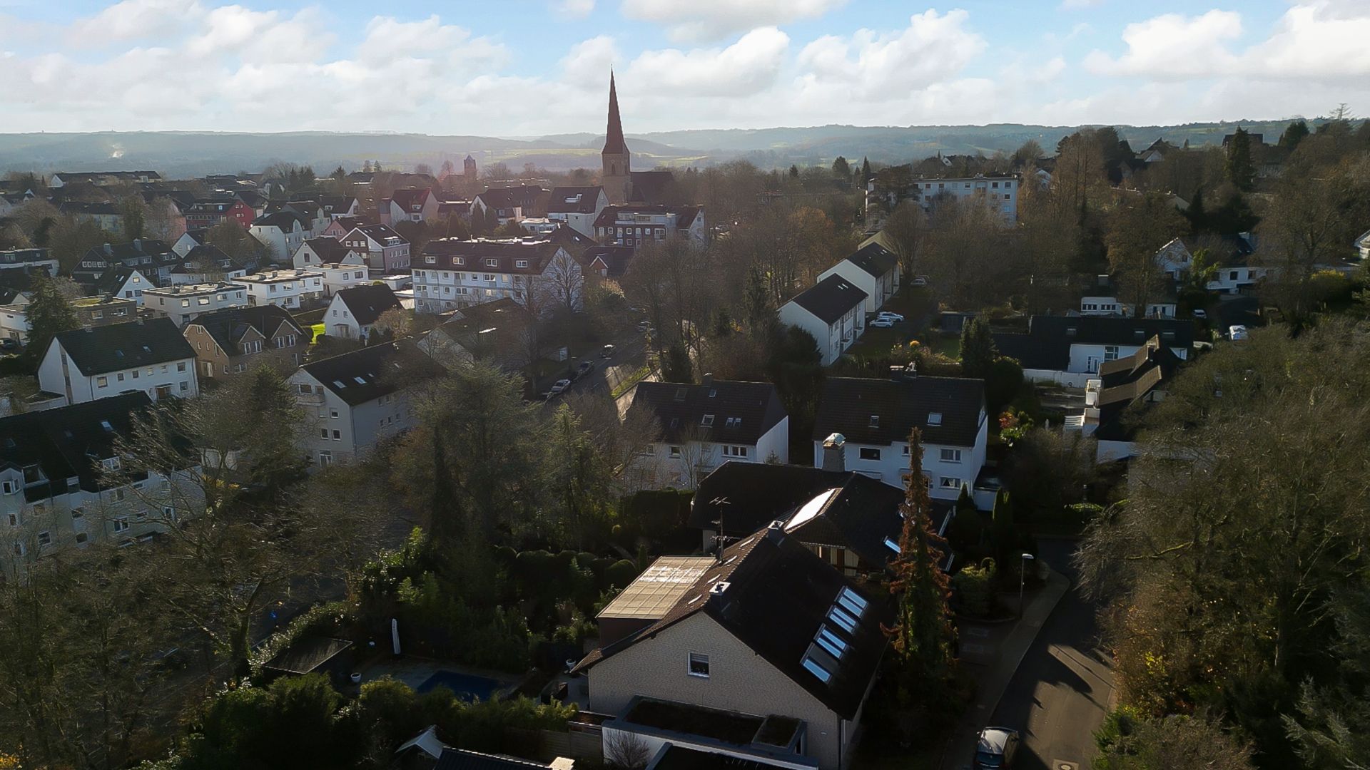 Luftaufnahme eines Wohngebiets mit vielen Häusern und einer Kirche im Hintergrund.