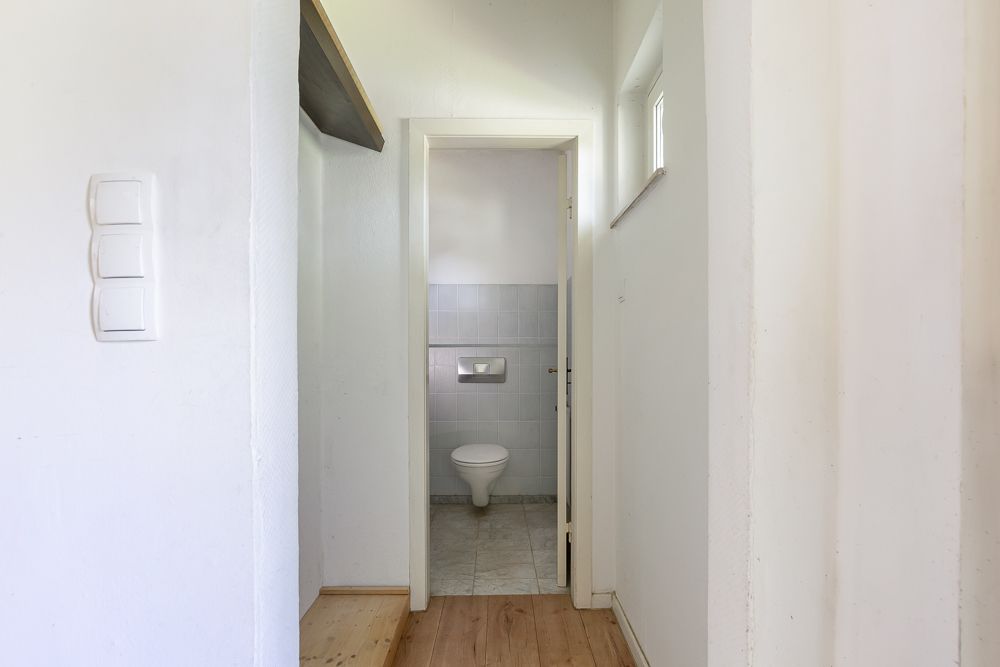 Heller Flur mit Blick auf eine kleine Toilette im Hintergrund.