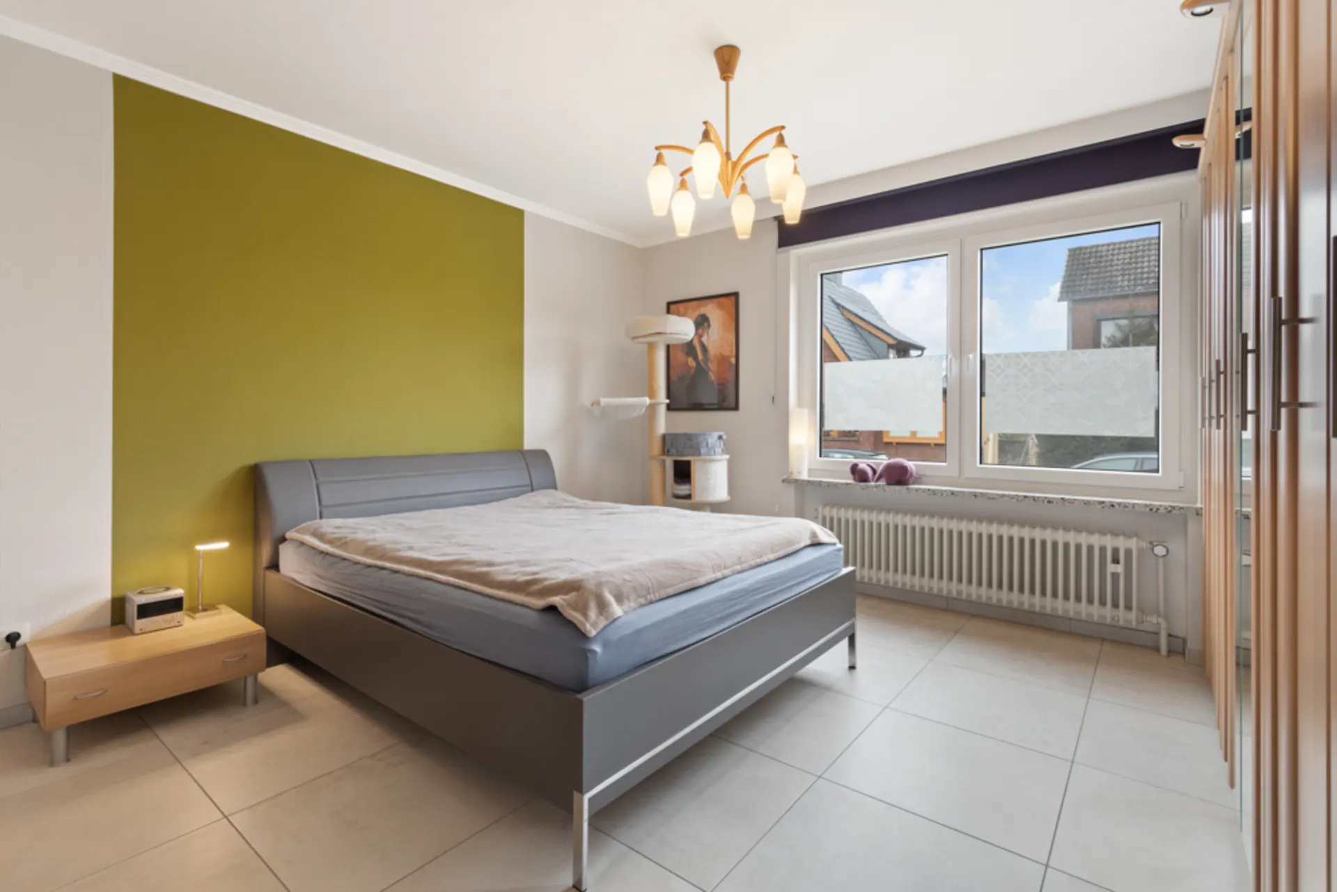 Modernes Schlafzimmer mit Doppelbett, Nachttisch, großem Fenster und Kleiderschrank.