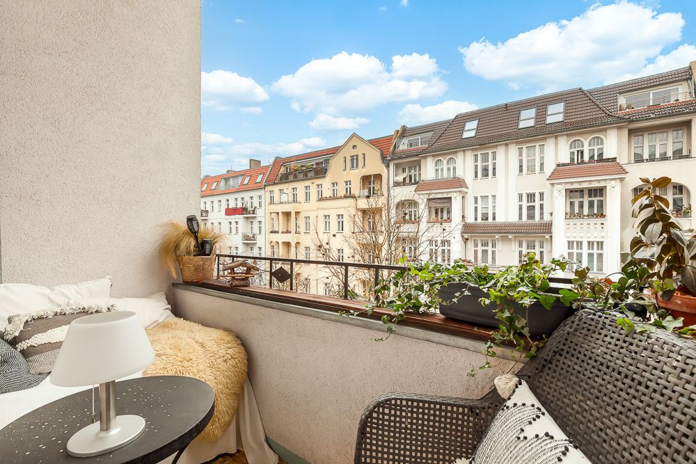 Gemütlicher Balkon mit Pflanzen, Sitzgelegenheit und Blick auf benachbarte Wohnhäuser.