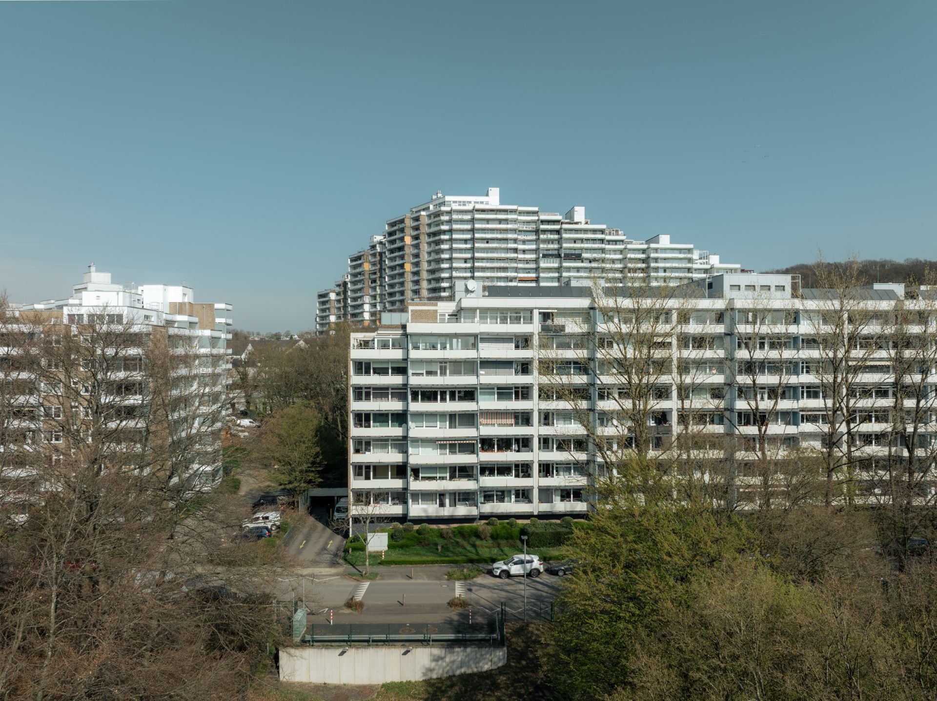 Mehrere große Wohngebäude mit Balkonen und Bäumen im Vordergrund.