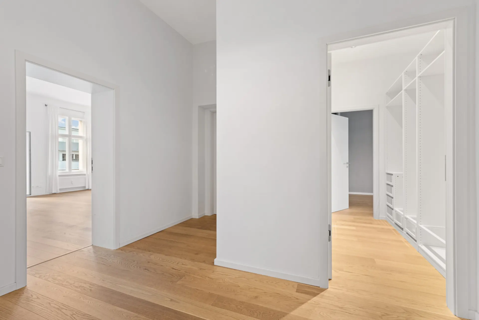 Heller Flur mit Holzboden, Zugang zu Zimmer und begehbarem Kleiderschrank, weiße Wände.
