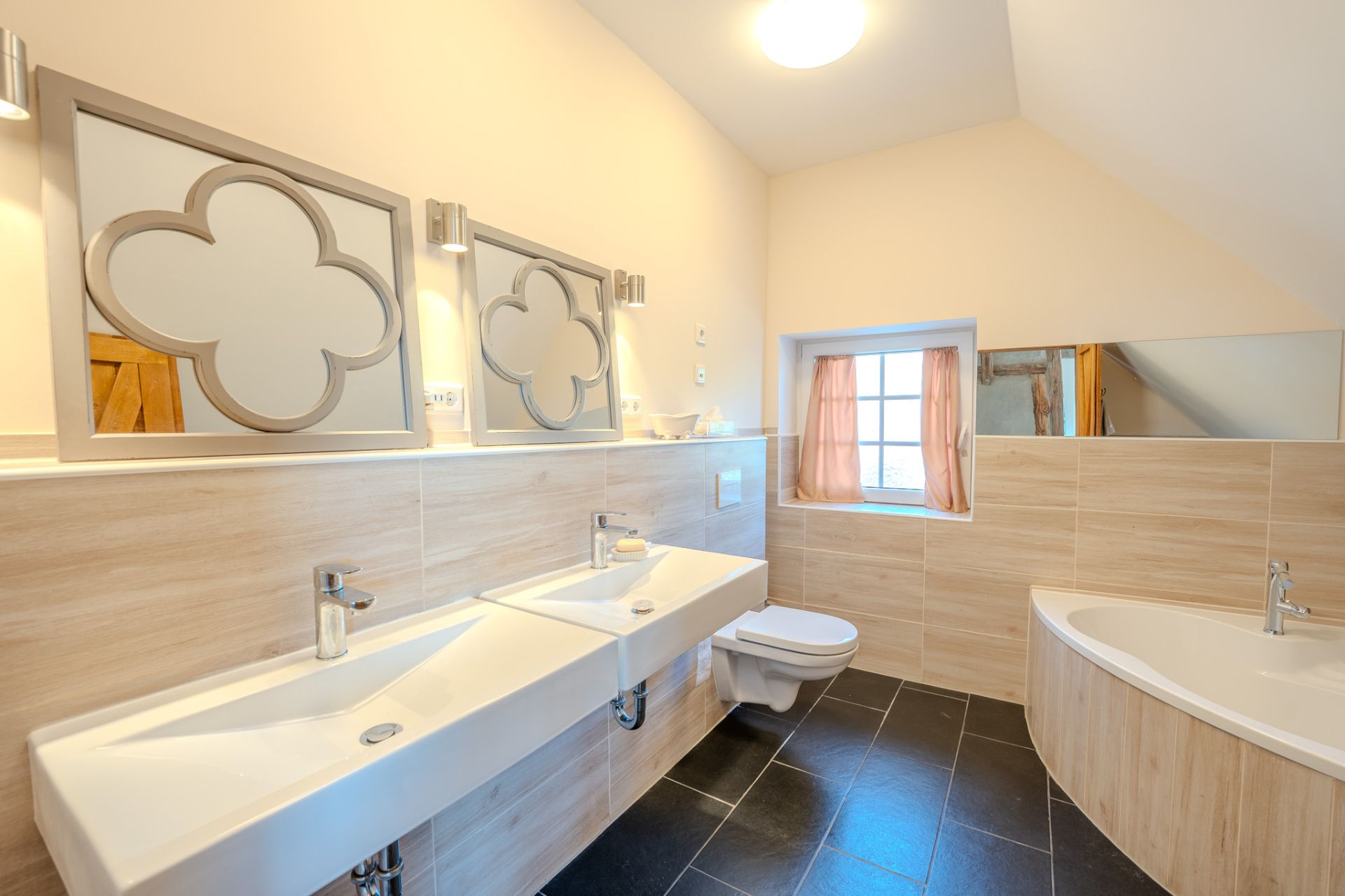 Modernes Badezimmer mit zwei Waschbecken, Wandspiegeln, Toilette und Eckbadewanne.