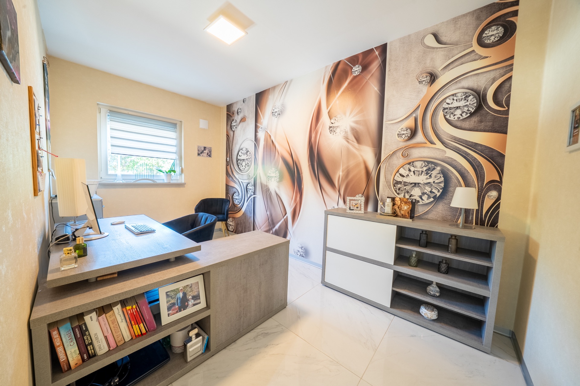 Modernes Arbeitszimmer mit Schreibtisch, Regal, Sessel und bunter Wandgestaltung.