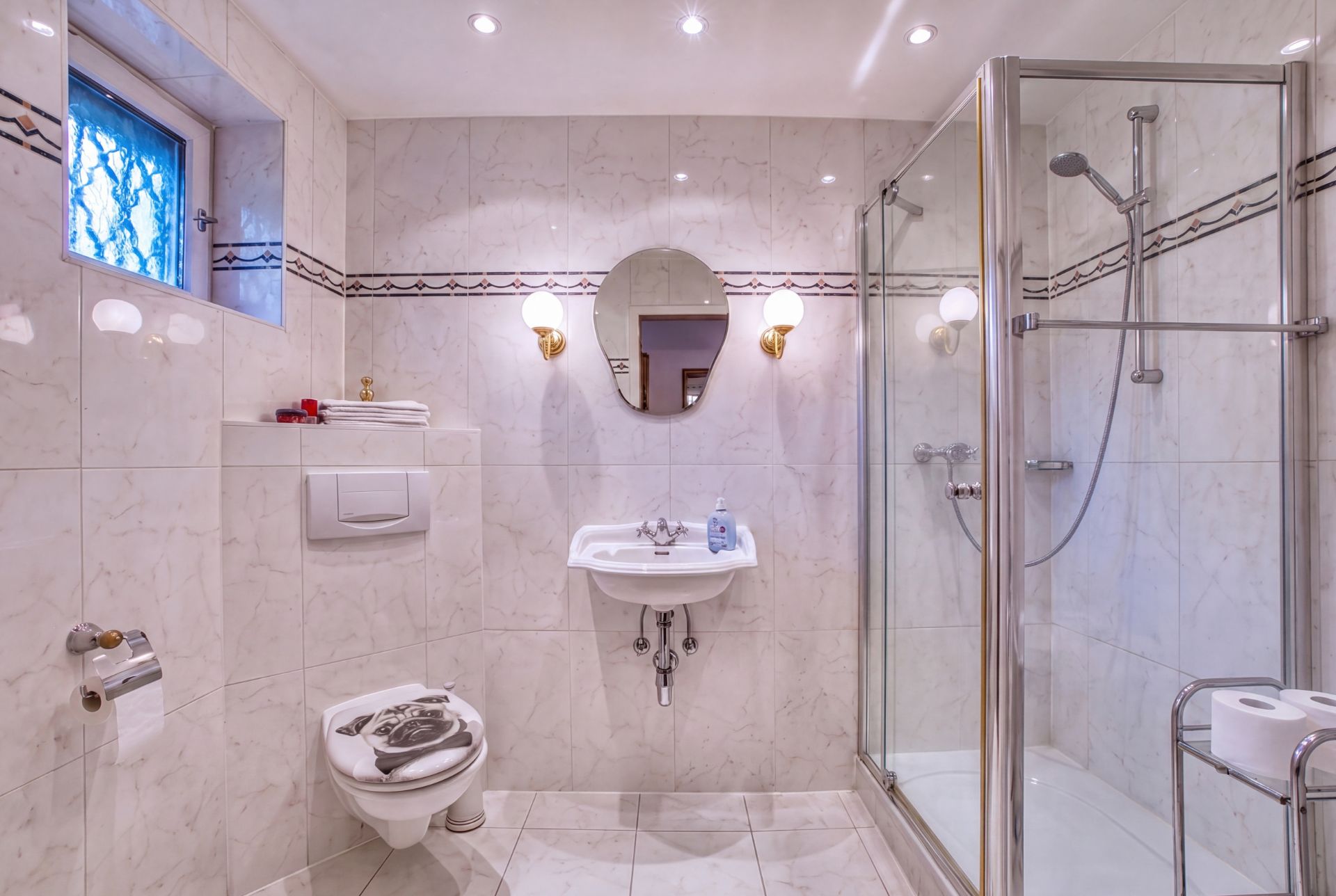 Modernes Badezimmer mit Dusche, WC, Waschbecken, Spiegel und gefliestem Boden.