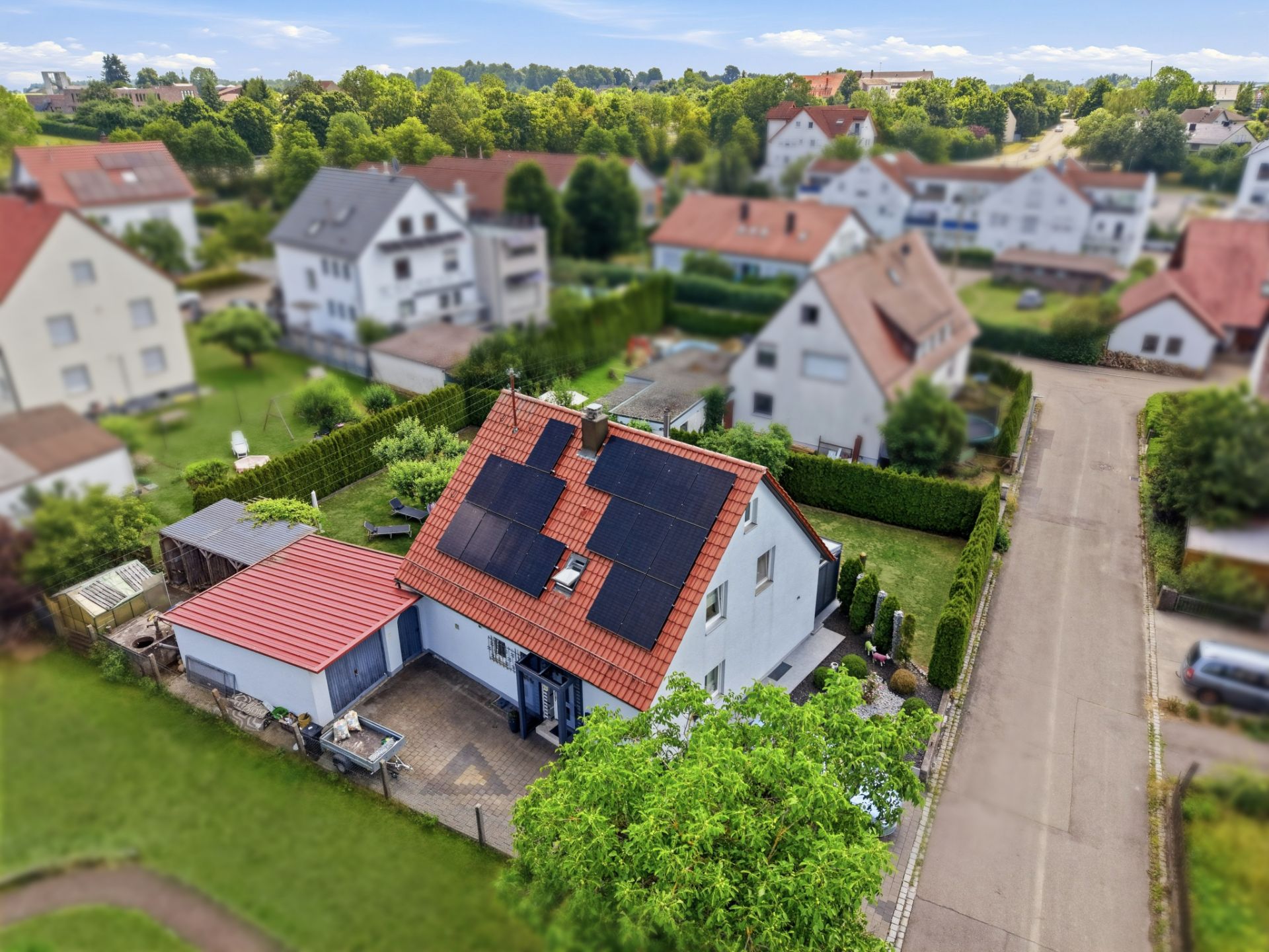 Einfamilienhaus mit Solarpanels auf dem Dach, umgeben von Garten und Nachbarhäusern.