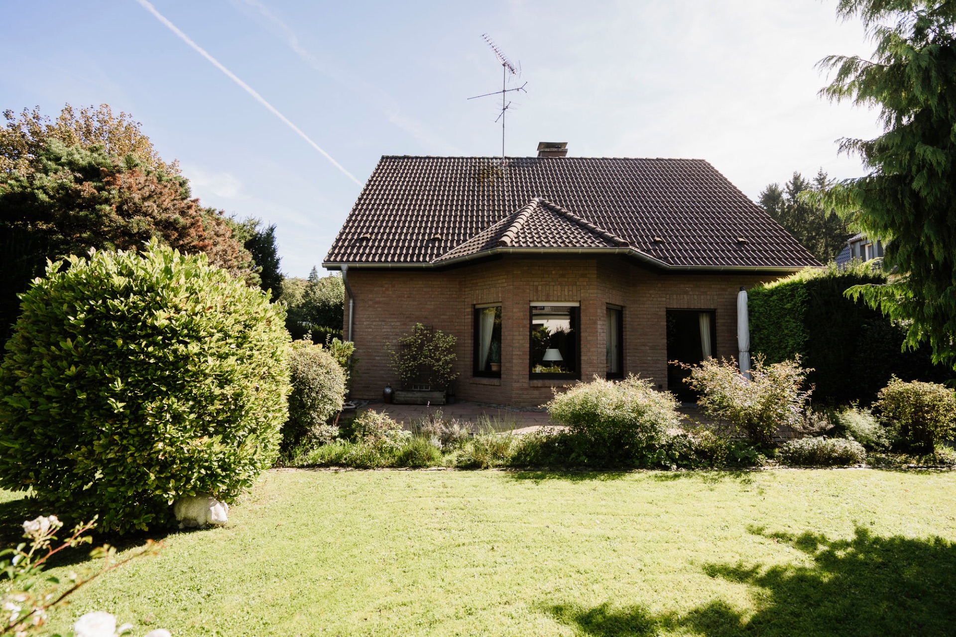 Einfamilienhaus mit Satteldach und Garten im Vordergrund.