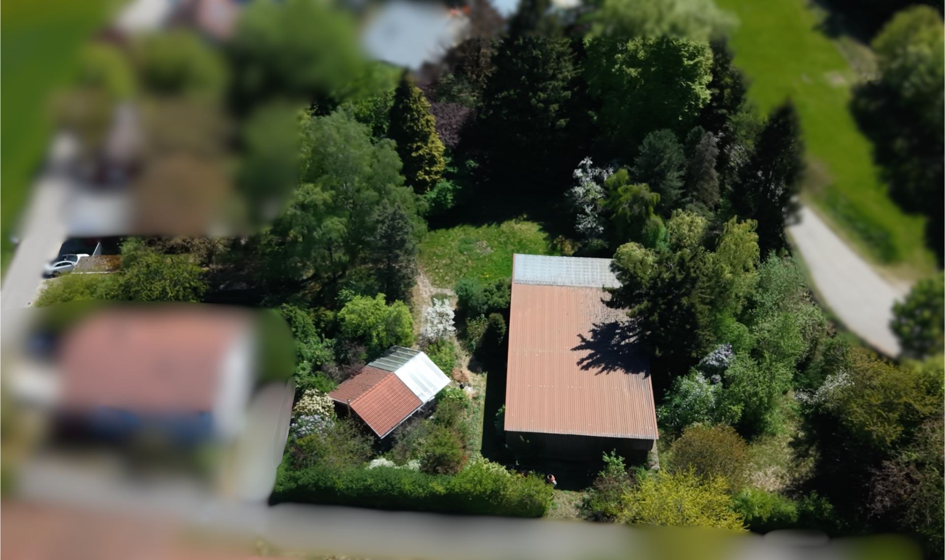 Vogelperspektive auf ein Grundstück mit zwei Gebäuden und viel Grünfläche.