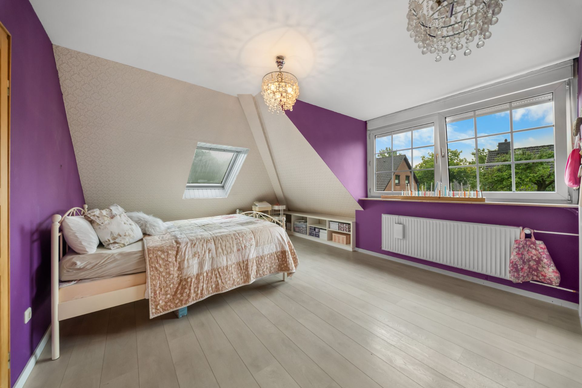 Helles Schlafzimmer mit lila Wänden, Einzelbett und großem Fenster mit Blick nach draußen.
