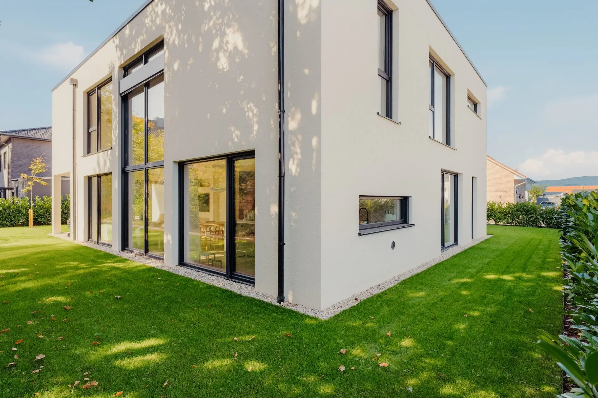 Modernes, zweistöckiges Wohnhaus mit großen Fenstern und gepflegtem Rasen.