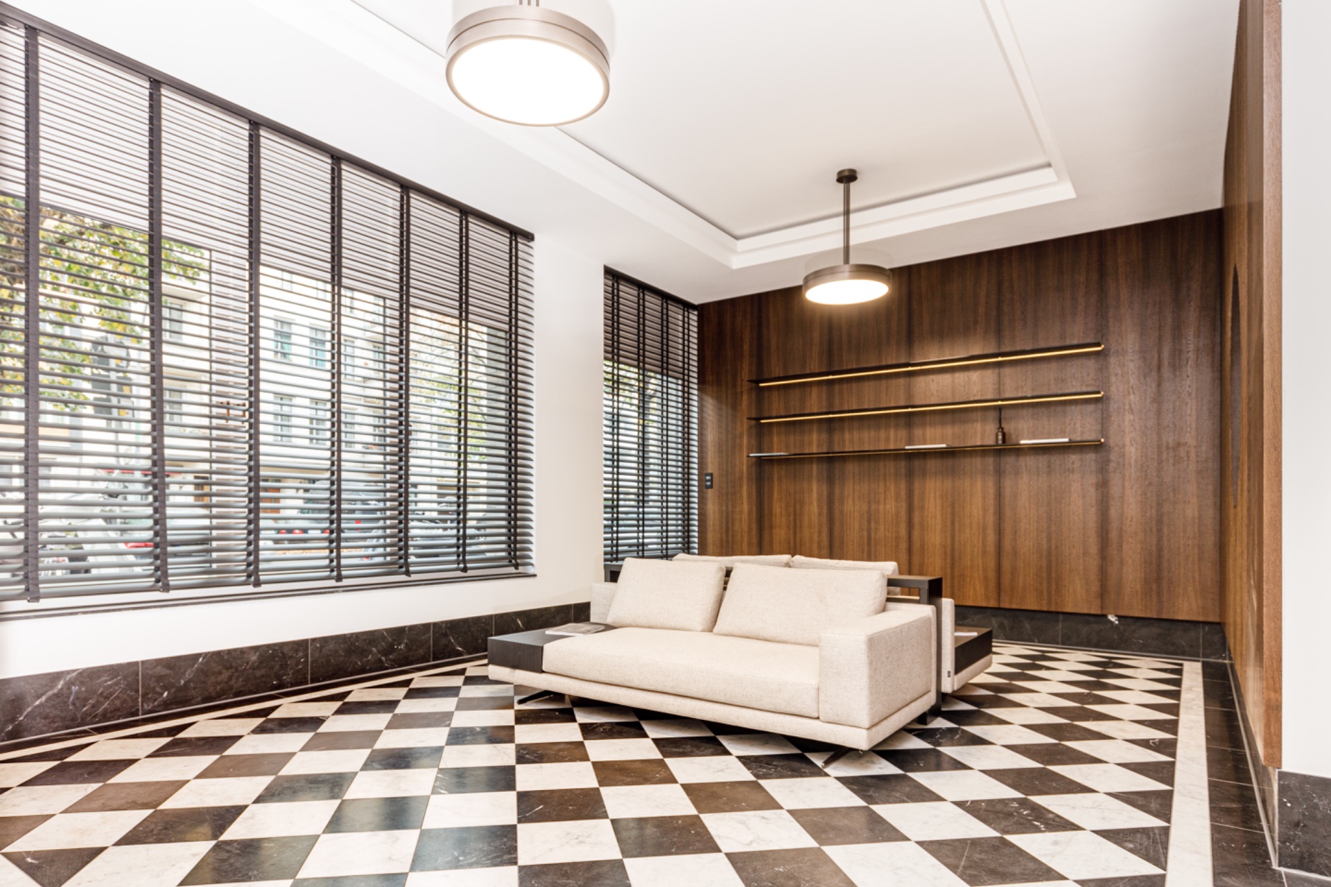 Modernes Wohnzimmer mit cremefarbenem Sofa, Holzwand und schwarz-weiß kariertem Boden.