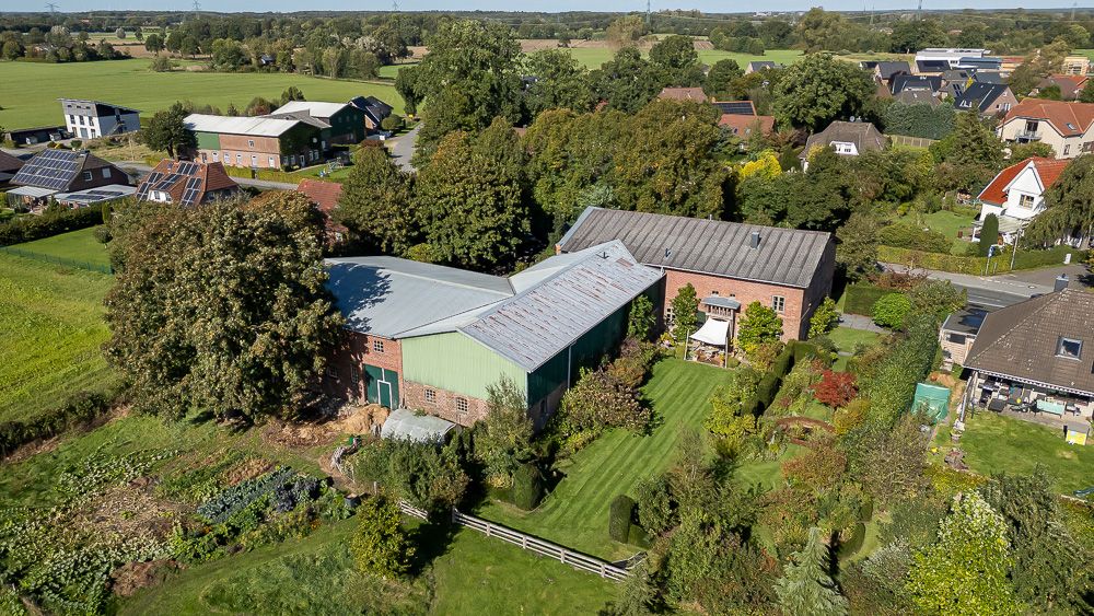 Luftaufnahme eines Bauernhofs mit mehreren Gebäuden und großem Garten in ländlicher Umgebung.