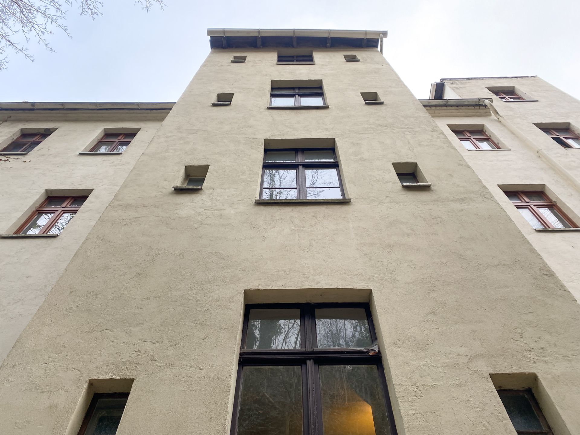 Blick nach oben auf eine Wohnhausfassade mit mehreren Fenstern.
