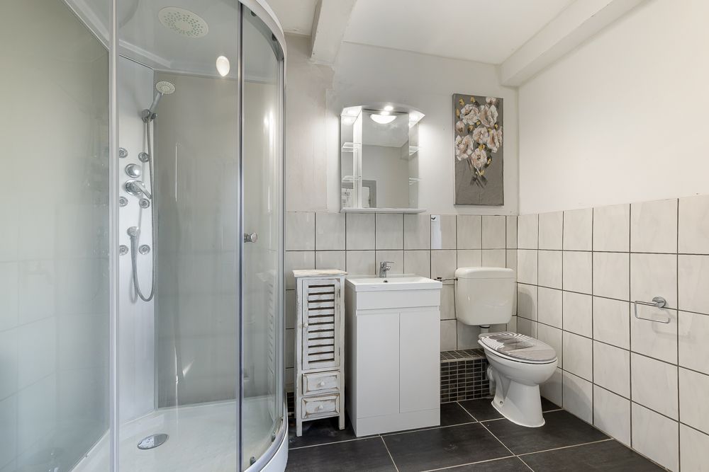 Modernes Badezimmer mit Dusche, Waschbecken, WC und Fliesenboden.