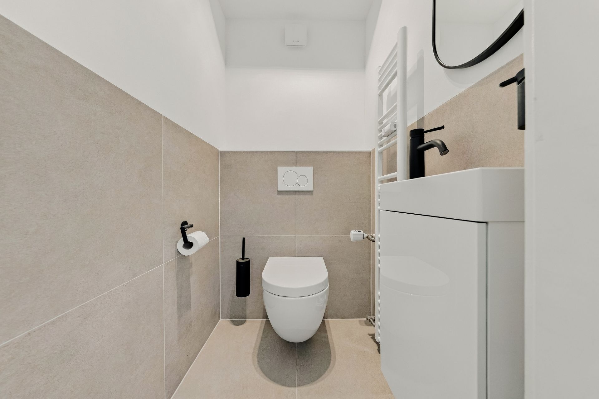 Modernes, kleines Badezimmer mit Wand-WC, Waschbecken, Spiegel und Handtuchheizkörper.