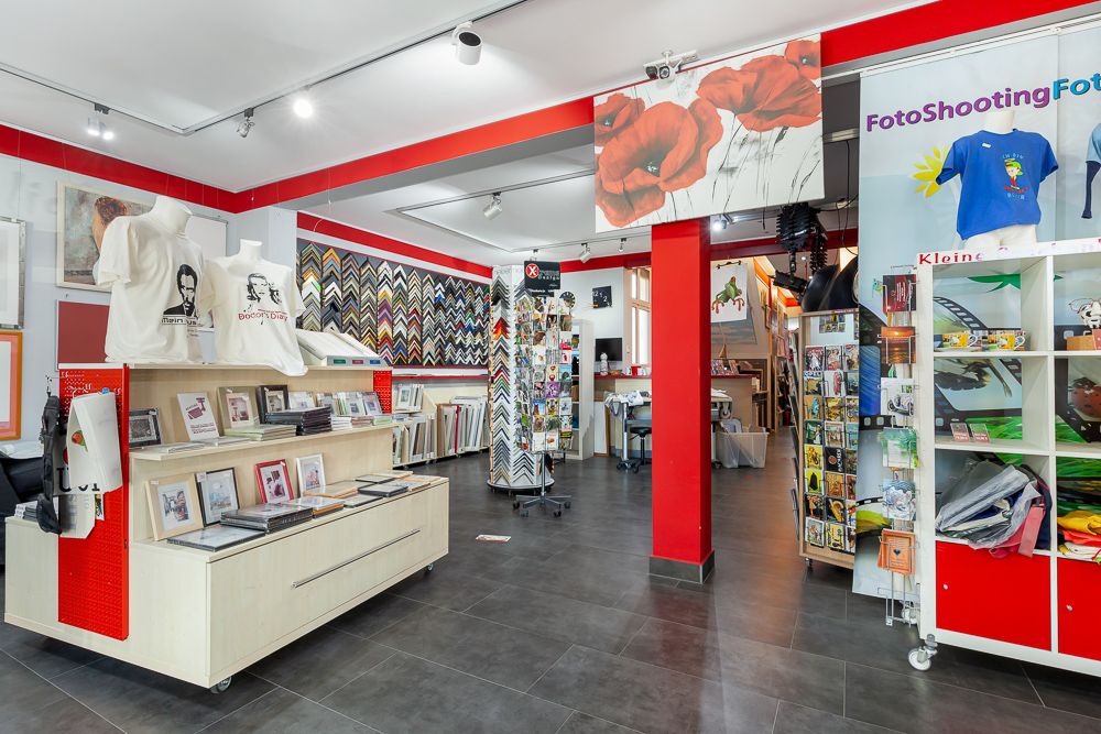 Heller Raum mit Fotoprodukten, T-Shirts und Bilderrahmen an Wänden und Regalen.