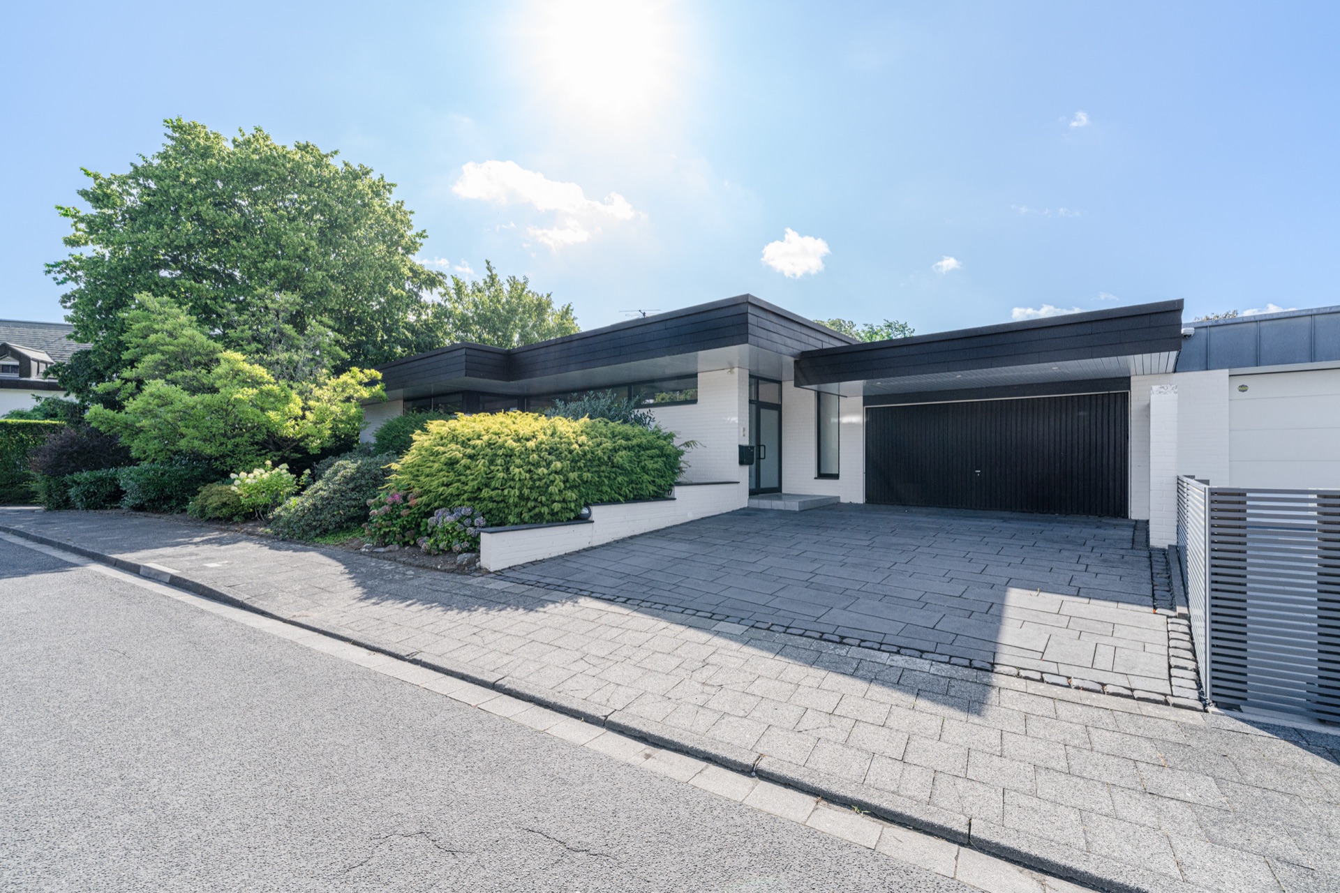 Modernes, einstöckiges Wohnhaus mit großer Einfahrt, Garage und gepflegtem Vorgarten.