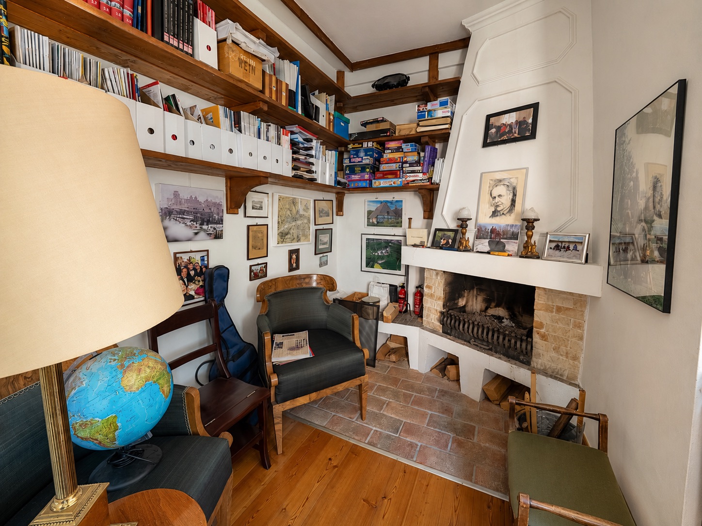 Gemütliches Arbeitszimmer mit Kamin, Regalen voller Bücher und Stühlen.